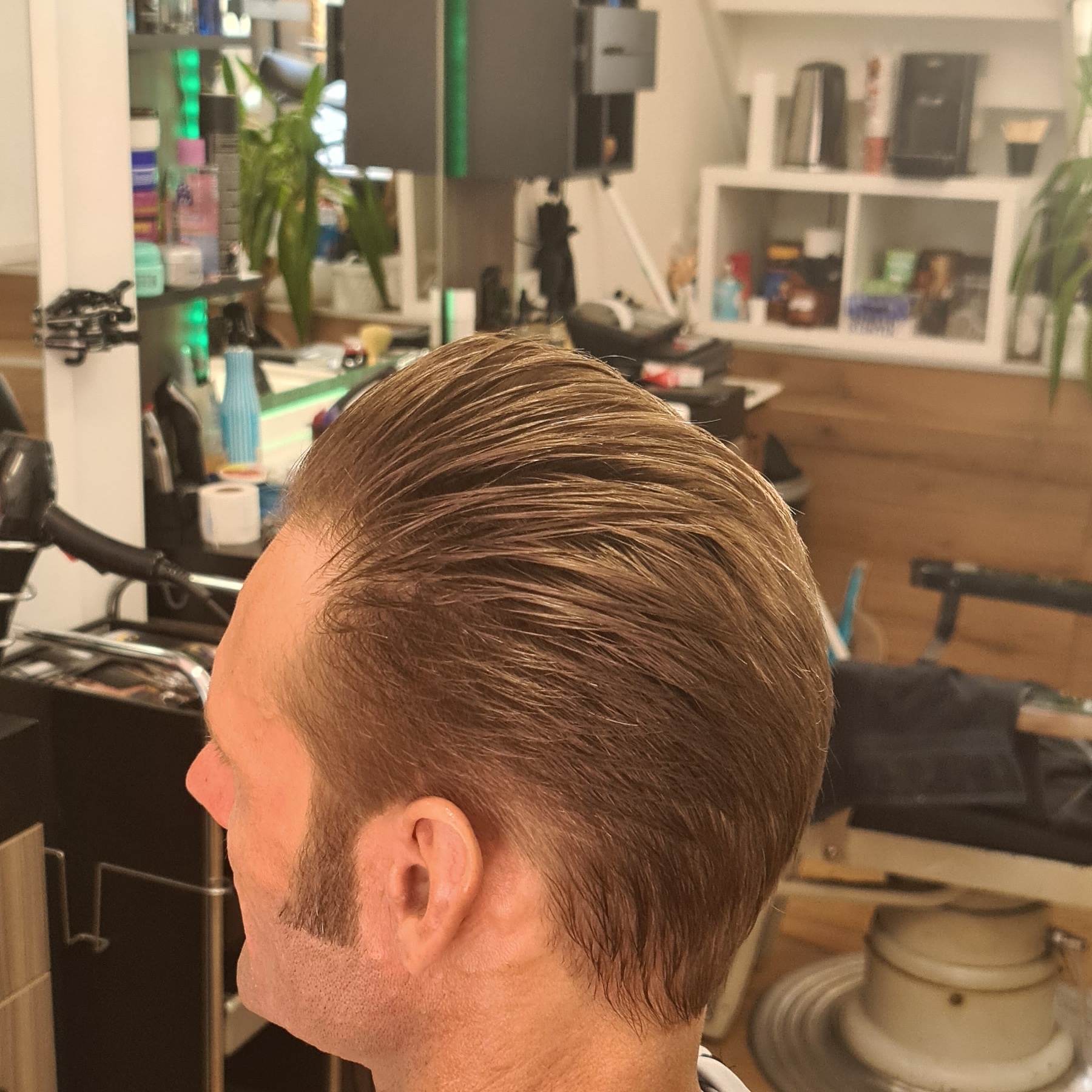 Heer met een naar achteren gekamde coupe, van opzij gezien in de salon